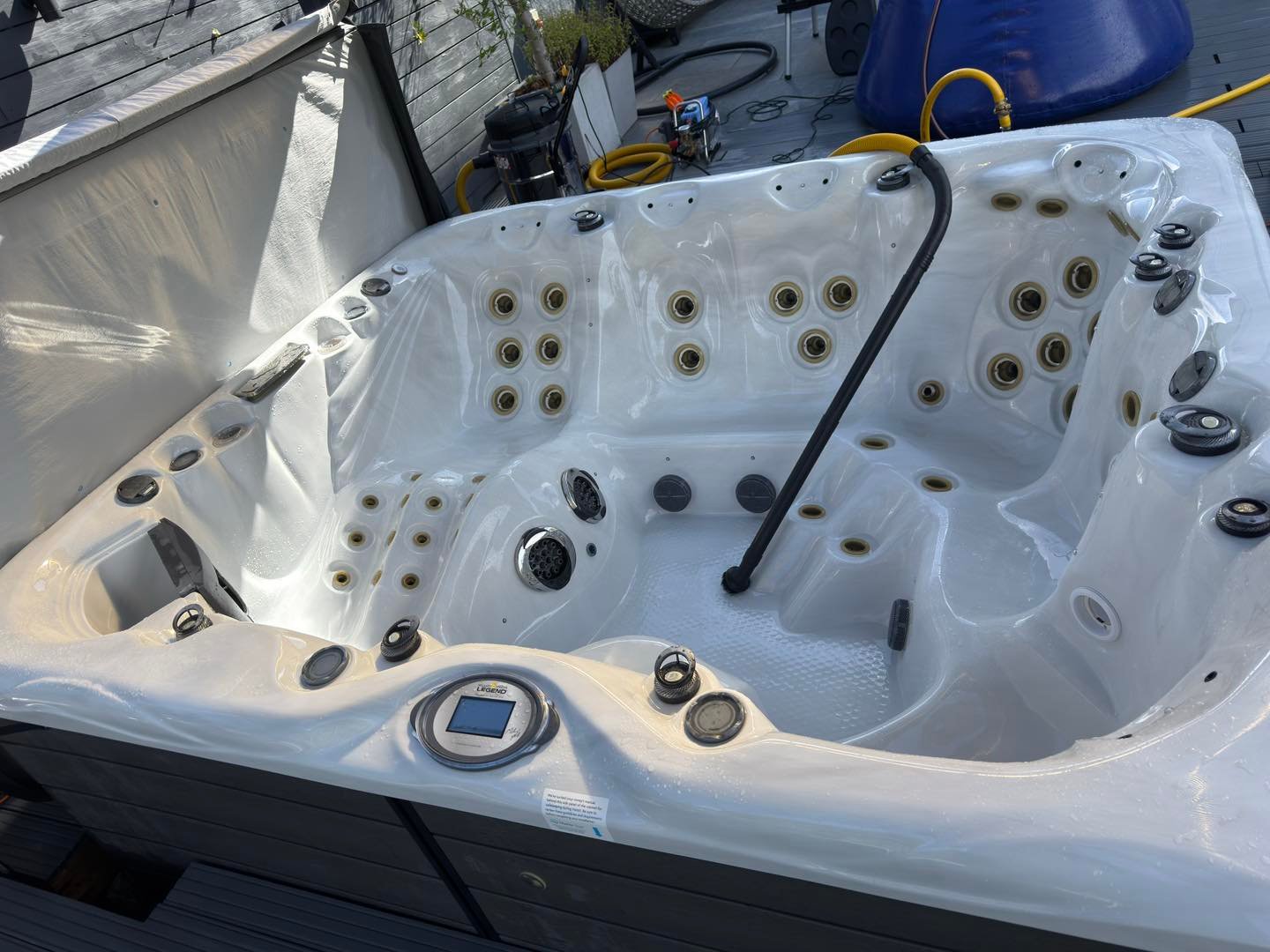 A drained hot tub shell being professionally vacuumed to remove all remaining water from the plumbing.